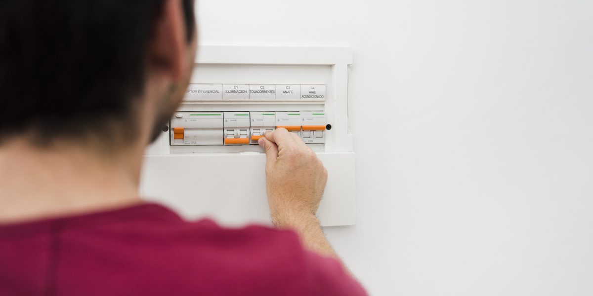 Person switching a breaker in a home electrical panel, illustrating circuit safety