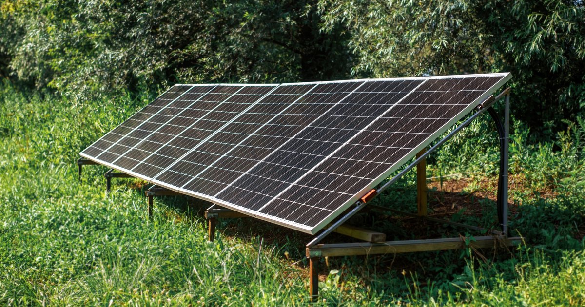 Large solar panel on a ground stand in a green yard, illustrating a ground-mounted solar panel (stock photo)